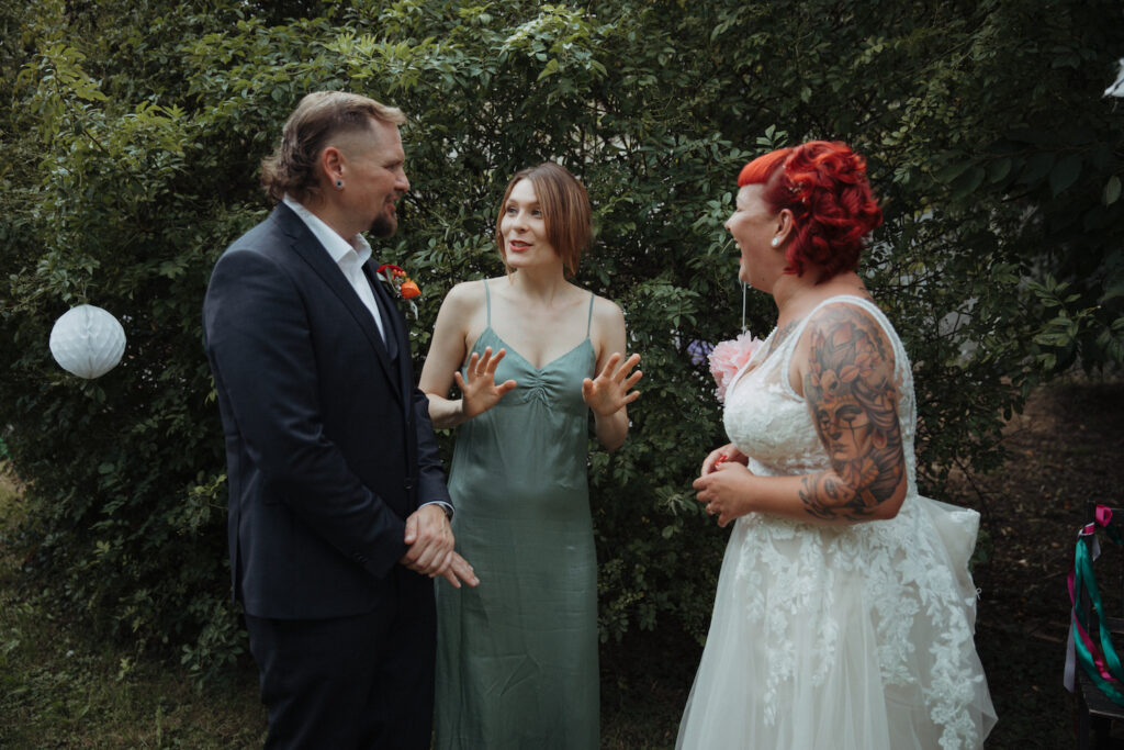Bräutigam, Traurednerin und Braut in einem Garten